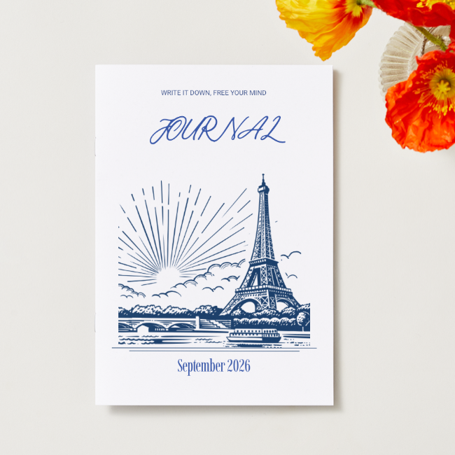 Mindful Journal September 2026 — A5-Heft in Händen gehalten, weißes Cover mit blauer Eiffelturm-Illustration und Schriftzug 'Write it down, free your mind'